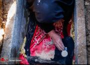 عکس/ مادر شهید طارمی فرزندش را داخل قبر گذاشت